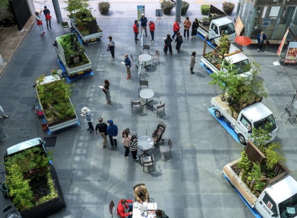 Aerial image of several small white kei-trucks, each with a Japanese style garden constructed in their cargo-beds. Via Spoon and Tamago blog. 